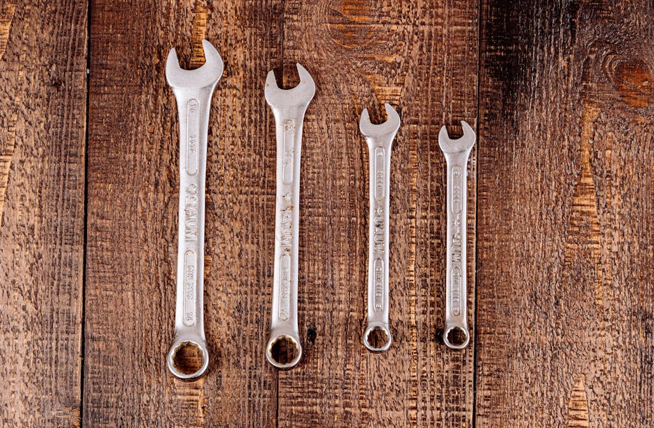 Flat lay of four metal wrenches on a rustic wooden surface, ideal for workshop or DIY themes.